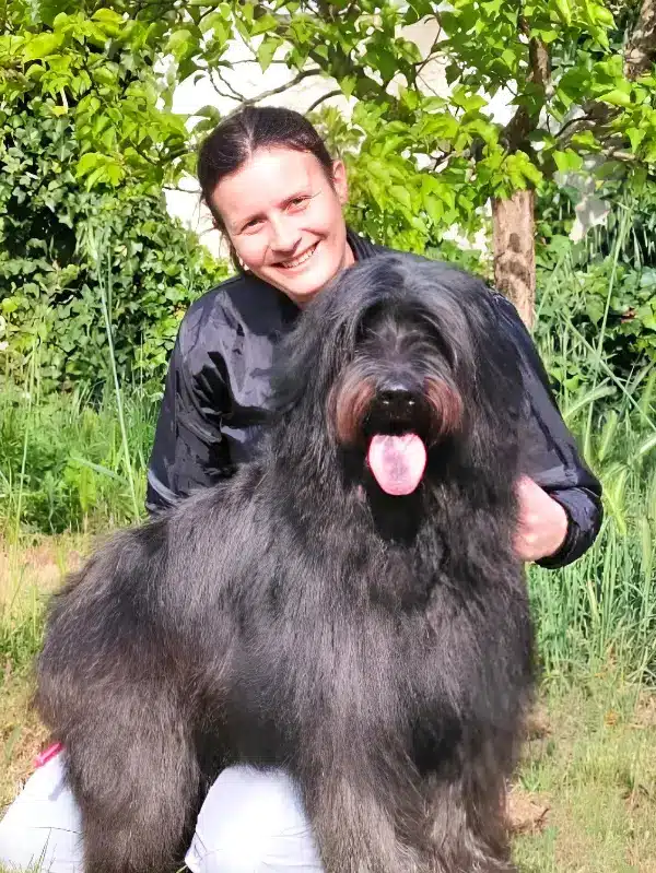 St&eacute;phanie, g&eacute;rante de Love dog avec un chien noir sur ses genoux &agrave; la campagne